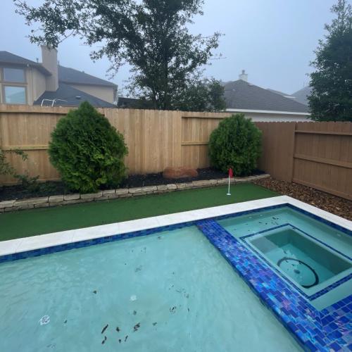 turf putting green in backyard next to pool